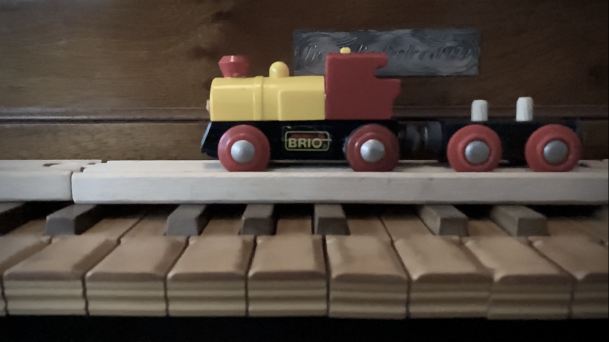 Toy train on rails and harpsichord keyboard.